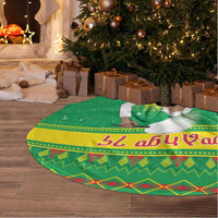 Green Christmas tree skirt with colorful patterned band and decorative trim