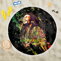 Black round beach blanket with fringed white edge, reggae-style graphic center