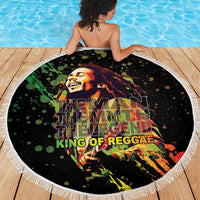 Black round beach blanket with white fringed border and colorful reggae portrait graphic