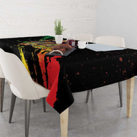 Black tablecloth draped over dining table with red, yellow, and green paint strokes