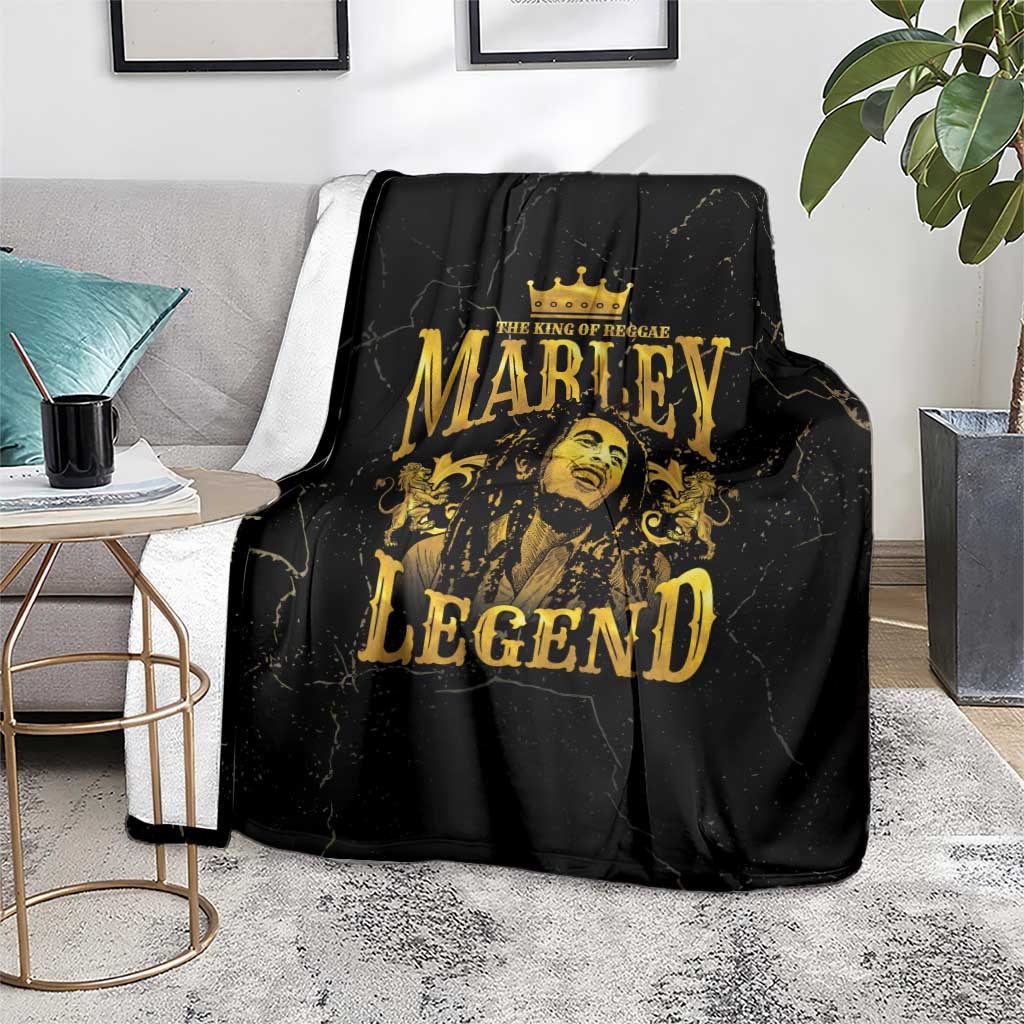 Black fleece blanket with gold Marley Legend crowned portrait, laid on rug