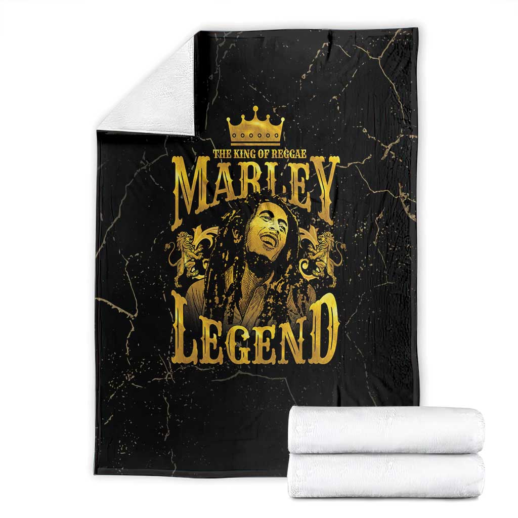 Black fleece blanket with gold Marley Legend crowned portrait, stacked with white rolls