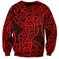 Red crewneck sweatshirt with bold dark Maori-style swirling pattern, long sleeves
