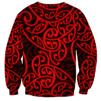 Red crewneck sweatshirt with black-and-red swirling Maori-style print, long sleeves
