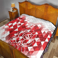 White and red quilt covering a bed, featuring red diamond pattern and rose “07”