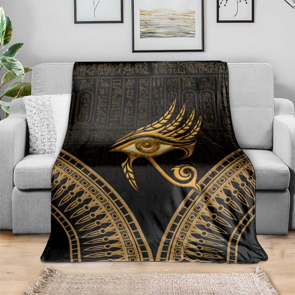 Gold feather and Eye of Horus design blanket draped over a gray sofa