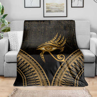 Gold feather and Eye of Horus design blanket draped over a gray sofa