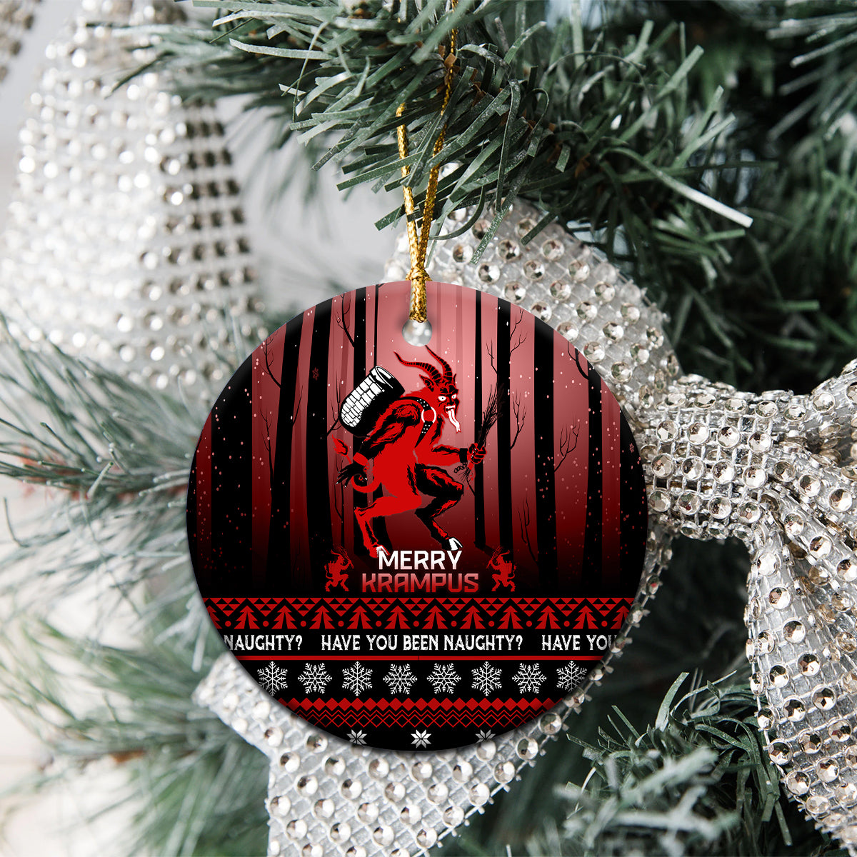 Black ceramic Christmas ornament with red Krampus artwork, hanging loop, on evergreen branches.