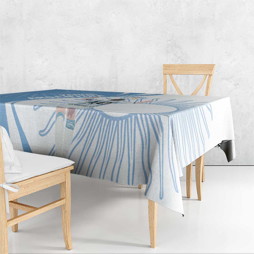 Sky blue tablecloth draped over wooden dining table with patterned corner drop