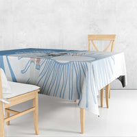 Sky blue tablecloth draped over wooden dining table with patterned corner drop