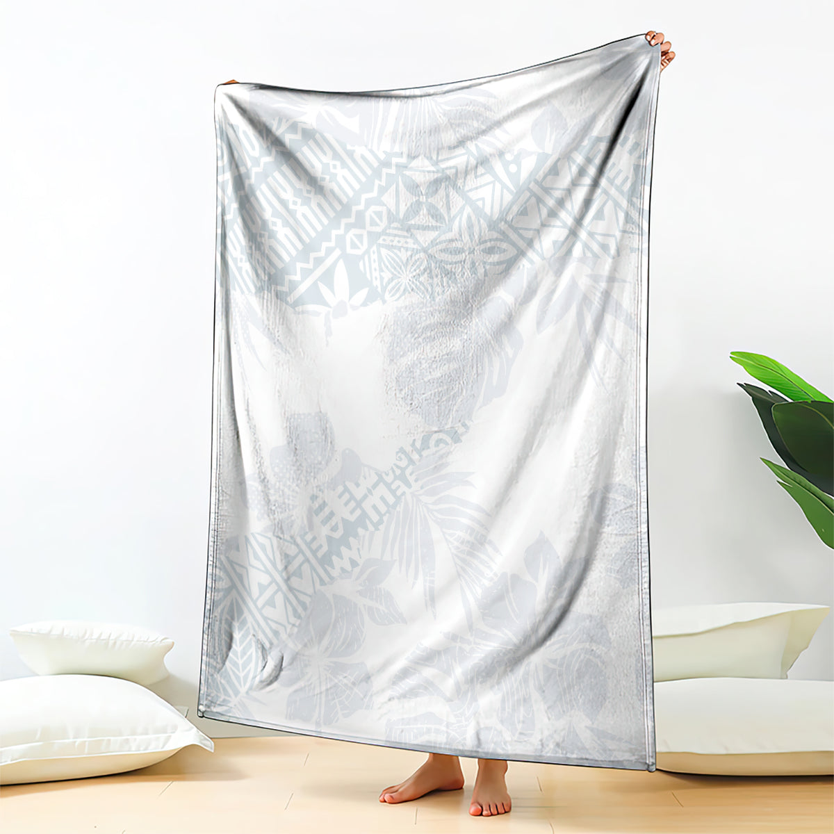 White throw blanket with light blue hibiscus and leaf pattern, draped over bed