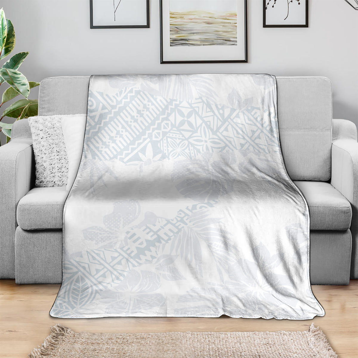 Light blue patterned white throw blanket folded over a gray sofa