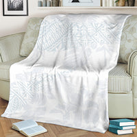 White throw blanket with light blue botanical pattern on a beige armchair