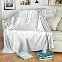 White throw blanket with light blue hibiscus and leaf motif across a couch