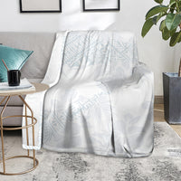 White throw blanket with light blue botanical pattern draped on a gray chair