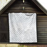 White quilt blanket with diamond stitching and black border, hung upright.