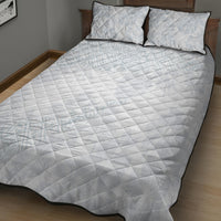 White quilt bed set on a bed, light blue patterning with black-edged pillowcases