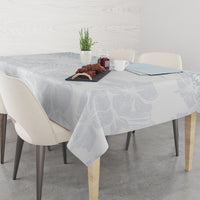 Light-blue floral tablecloth on a round dining table with chairs and serving items.