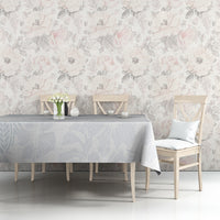 Light-blue floral tablecloth on a dining table with chairs against a floral wall.