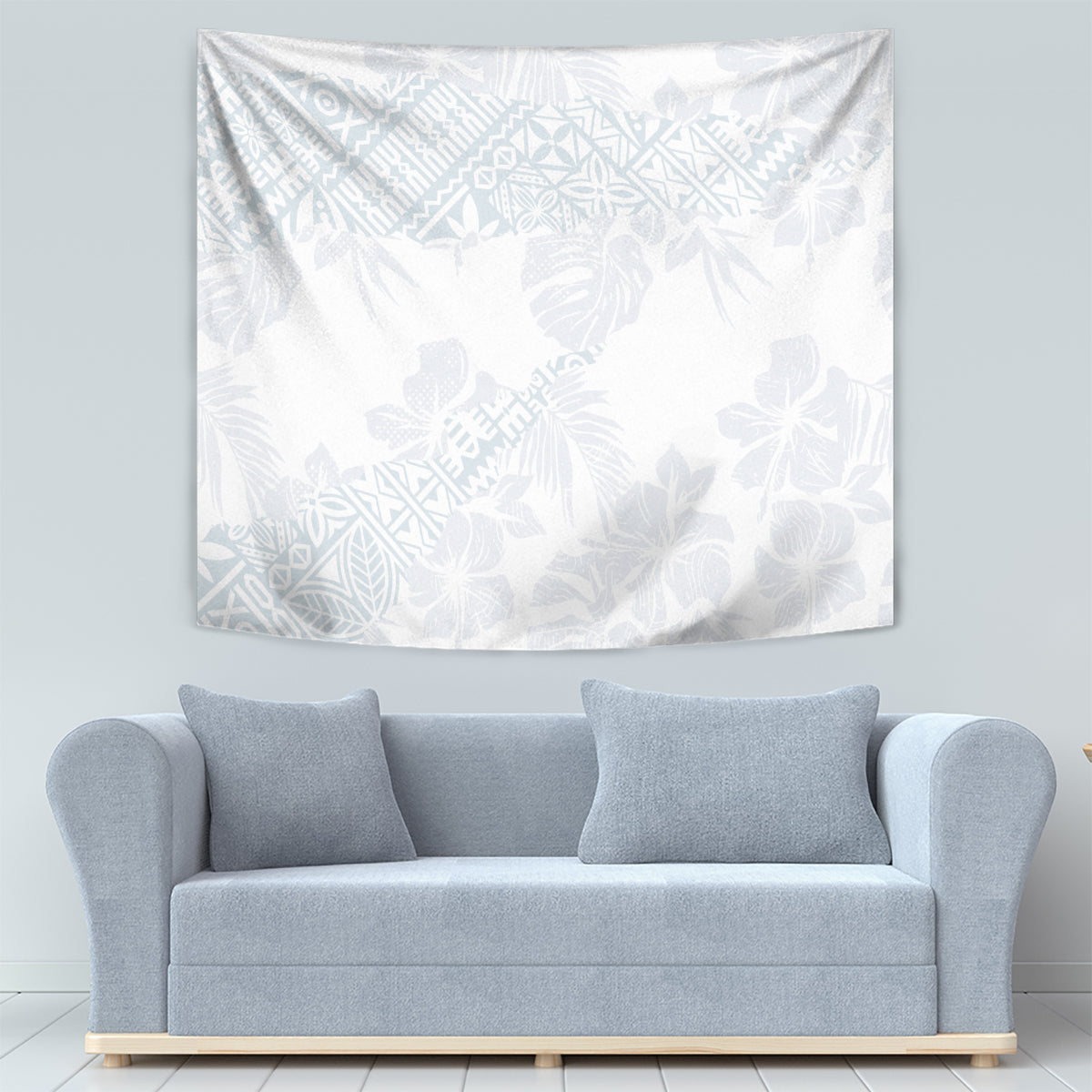 White tropical wall tapestry with light blue hibiscus and leaf design, above a sofa.