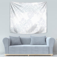 White tropical wall tapestry with light blue hibiscus and leaf design, above a sofa.