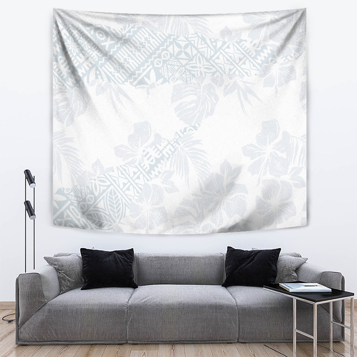 White tapestry with light blue floral and leaf pattern, displayed above a gray couch.