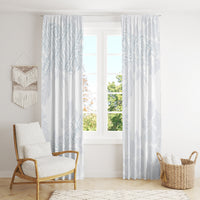 White curtains with light blue botanical pattern, hanging over window beside chair
