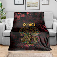 Sankofa heart throw blanket on grey sofa, dark red geometric blocks, gold-green heart emblem