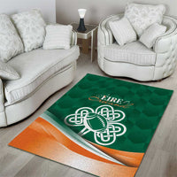 Green area rug with Celtic shamrock football emblem and orange edge stripe on light flooring