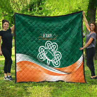 Green outdoor quilt blanket with Celtic knot emblem and orange-and-white bottom stripe.