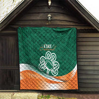 Green quilt blanket with Celtic knot logo, orange-and-white stripe, quilted diamond stitching.