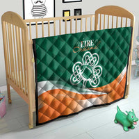 Green baby crib quilt with Celtic knot logo, orange-and-white stripe, and quilted diamonds.