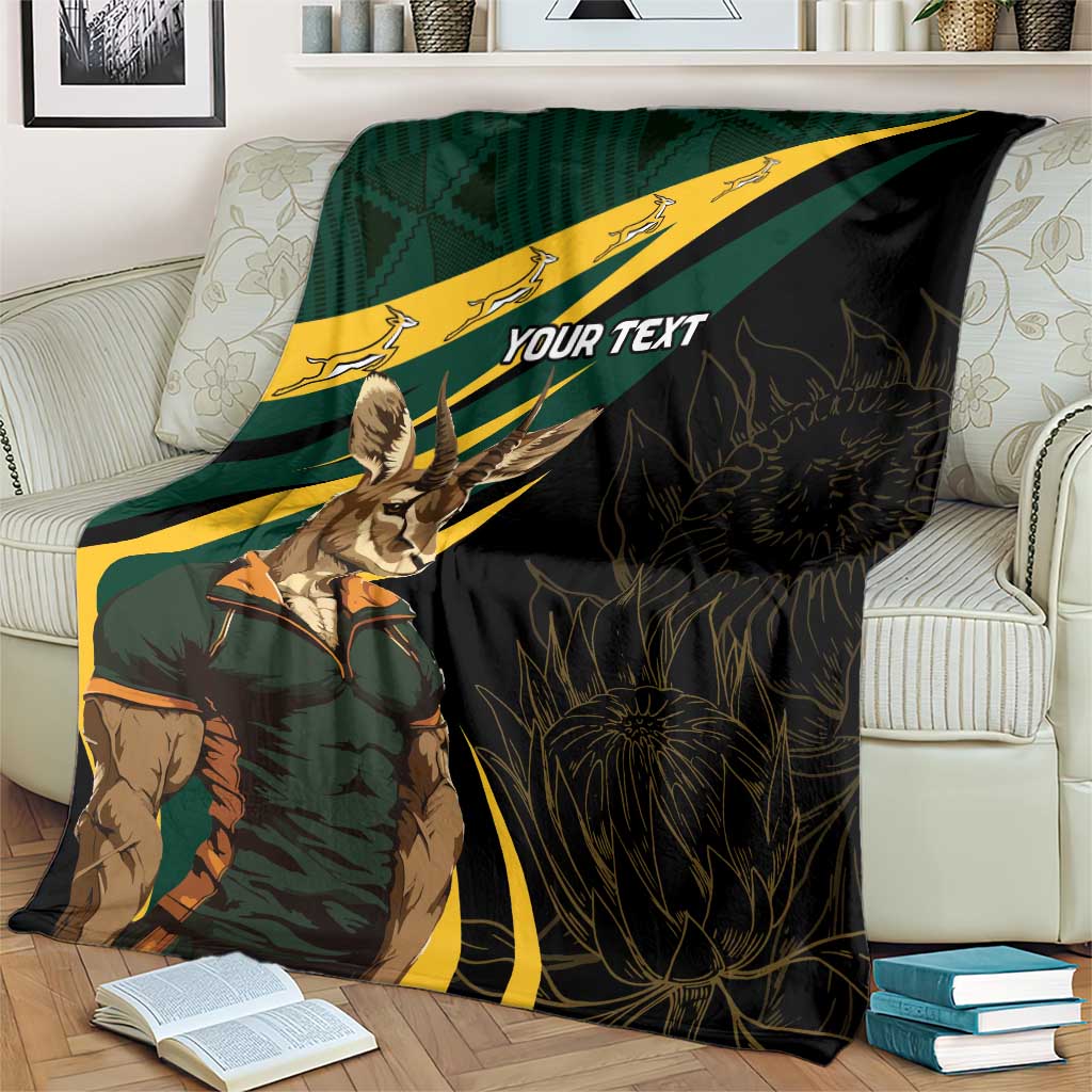 Personalized springbok mascot blanket on couch with “YOUR TEXT” and dark leafy pattern