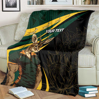 Personalized springbok mascot blanket on couch with “YOUR TEXT” and dark leafy pattern