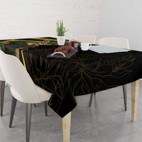 Black tablecloth draped on rectangular dining table with gold vine pattern