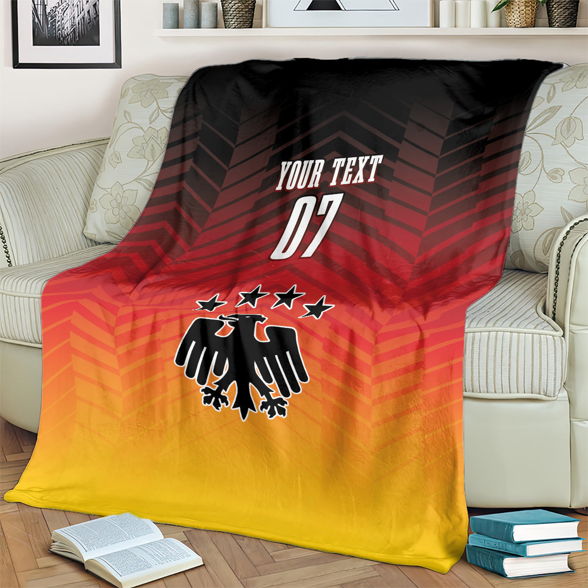 Football blanket draped on couch, red-to-yellow gradient with eagle emblem, stars, 'YOUR TEXT 07'