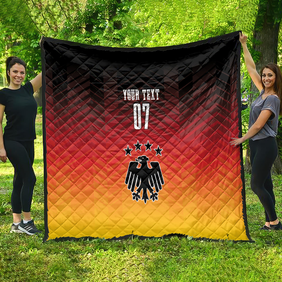 Germany football quilt blanket held on grass; black, red, yellow with eagle and three stars