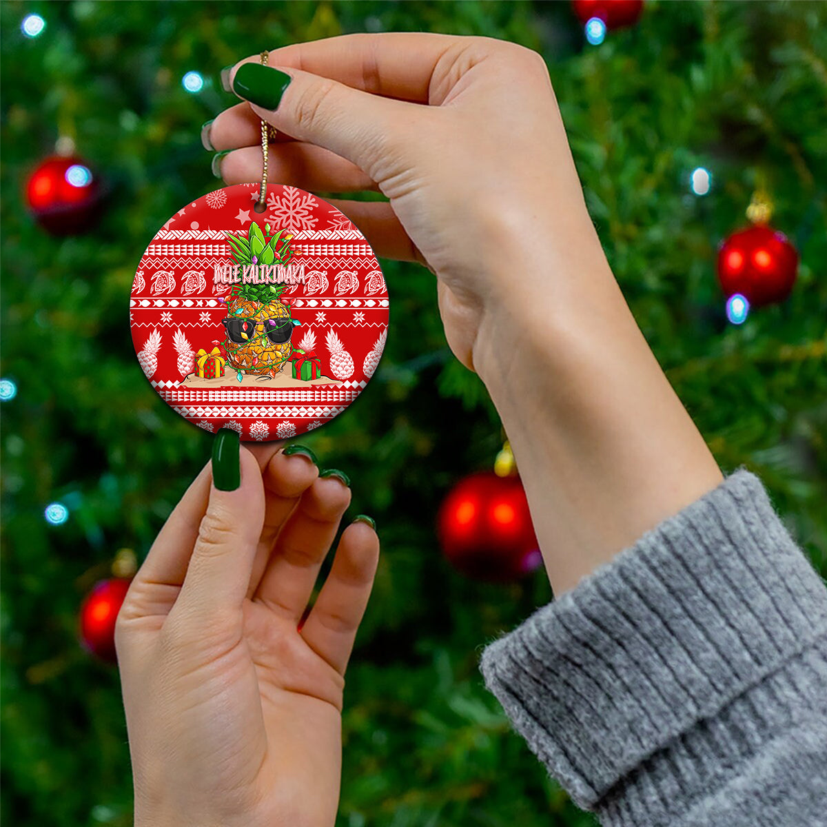 Red ceramic round Christmas ornament with pineapple scene and “Mele Kalikimaka”, held on string