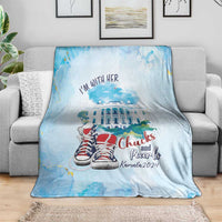 Light blue blanket showing 'I'm with her', a white building illustration, and red sneakers