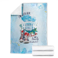 Light blue blanket, folded, with 'I'm with her' slogan, building art, and red sneakers