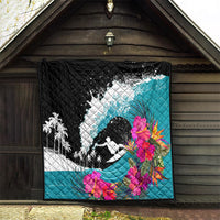 Black and teal quilt hung on a wall with surfer silhouette, white splash graphic, bright hibiscus.