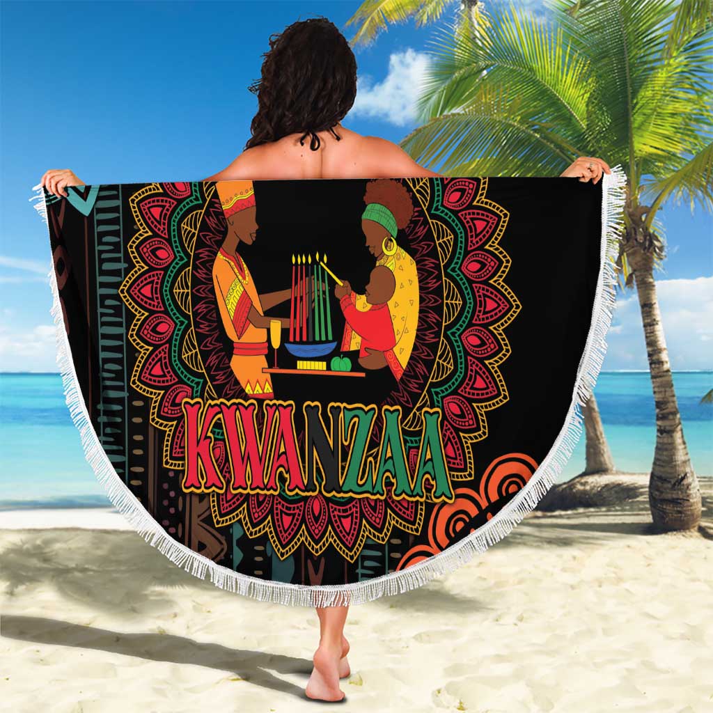 Round black Kwanzaa mandala beach blanket with white fringe, held up outdoors
