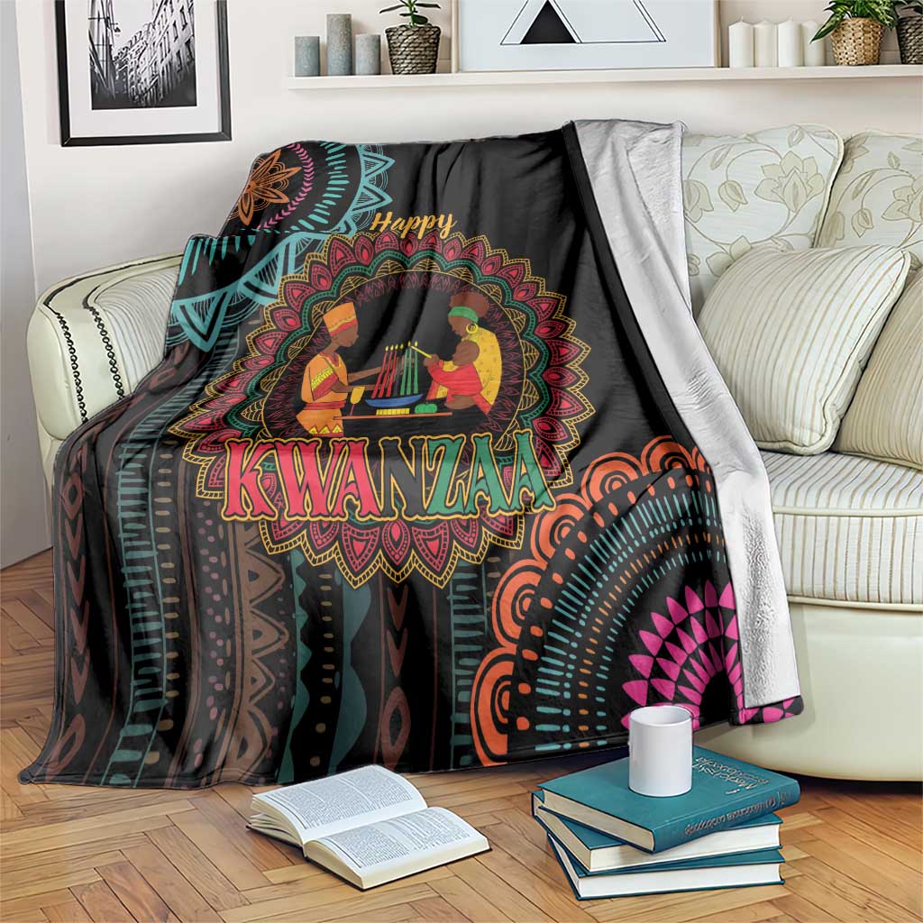 Black Kwanzaa mandala blanket with “Happy Kwanzaa” and seated figures, draped on sofa