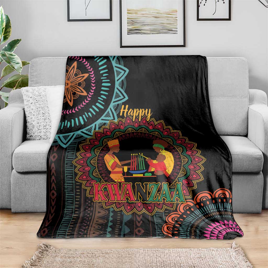 Black Kwanzaa mandala blanket with “Happy Kwanzaa” and figures, across gray couch