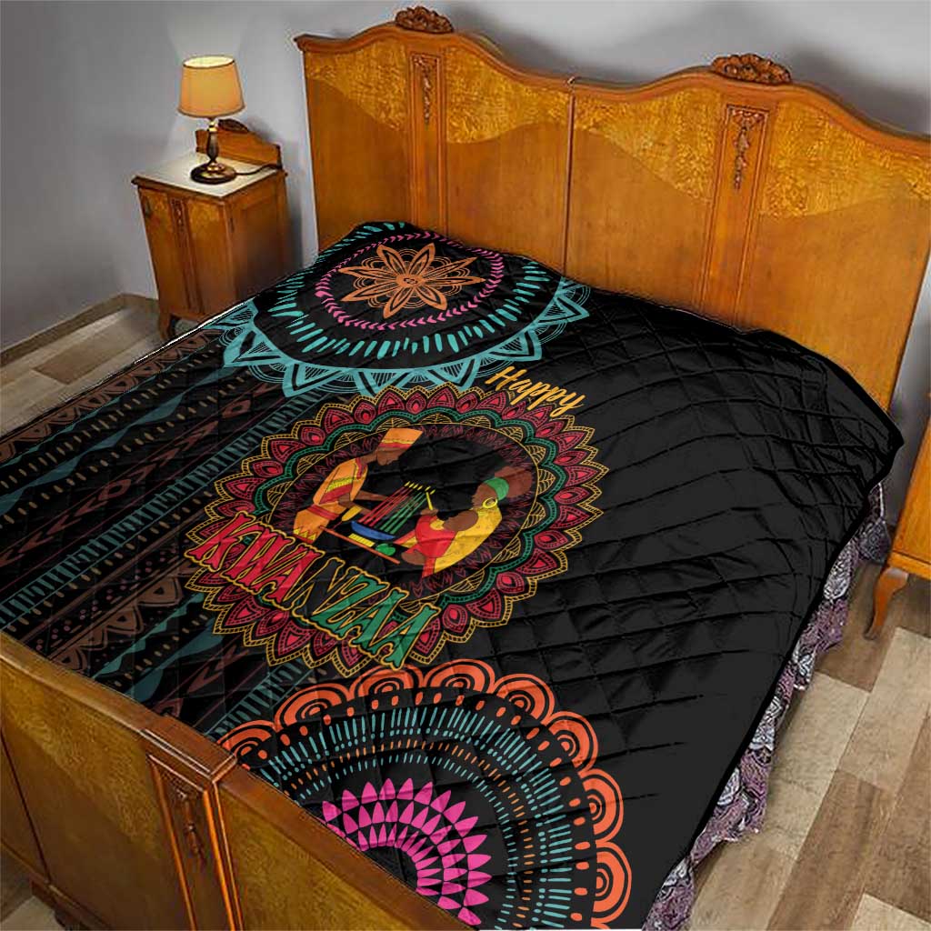 Black quilt on bed with colorful Kwanzaa medallion, “Happy” and “Kwanzaa” text