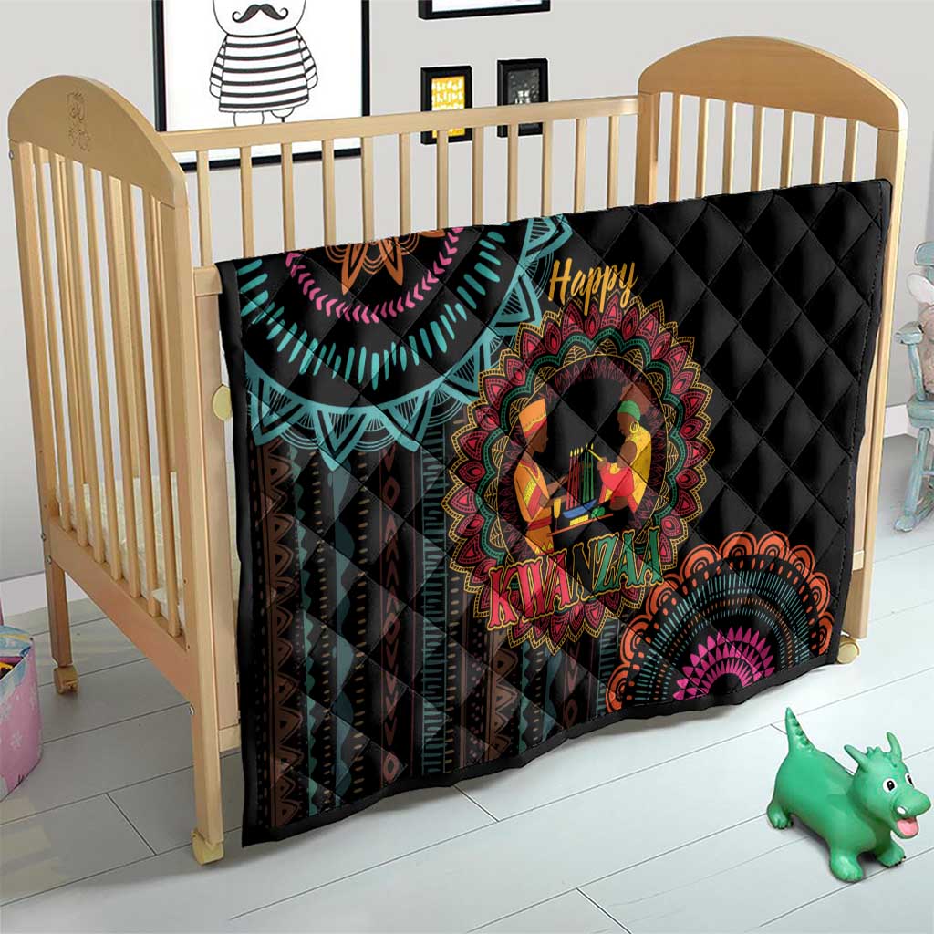 Black quilt on baby bed with colorful Kwanzaa mandala, “Happy” and “Kwanzaa” text