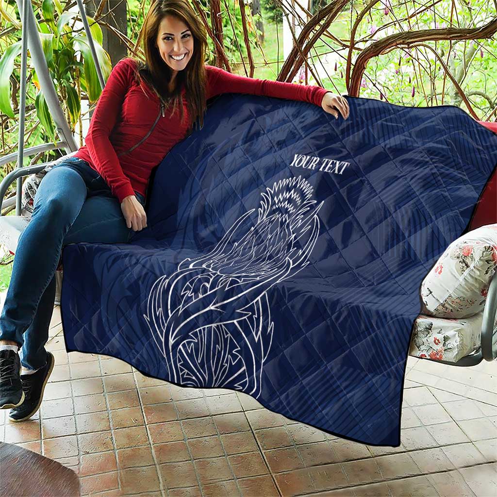 Blue quilt blanket with thistle line art and 'YOUR TEXT' spread out