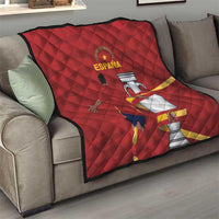Red quilt with diamond quilting and Spain crest graphic, spread on sofa