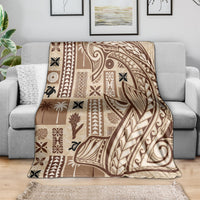 Beige tapa blanket with dark tribal pattern, spread over a gray sofa