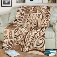 Beige tapa blanket with dark tribal pattern, draped over a light sofa